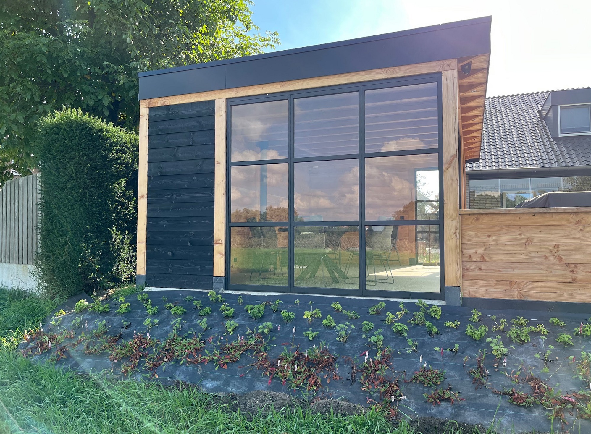 Tuinkamer met houten balken, een zwarte gevel en grote zwarte kozijnen